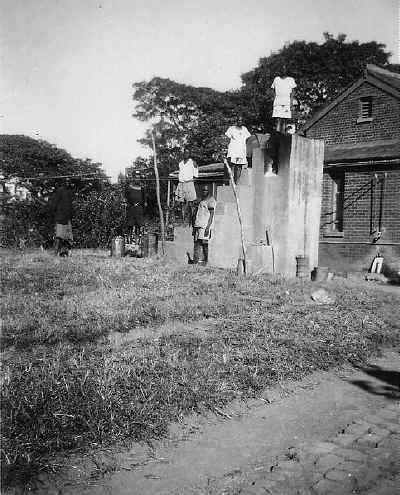 Prisoners employed filling the water drums which supplied bathing water to the house.
